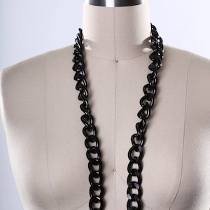 May include: A black chain necklace on a white dress form. The chain is thick and has large links.