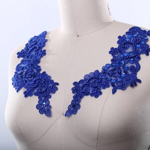 May include: Two pieces of royal blue lace applique with floral and scroll designs. The applique is embellished with sequins and beads. The lace is displayed on a mannequin.