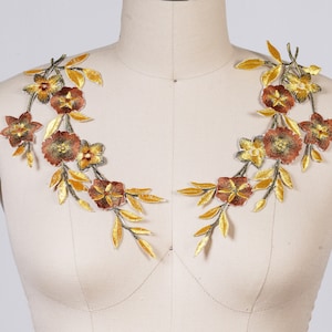 May include: Two gold and brown floral appliques with a leafy design. The appliques are perfect for adding a touch of elegance to clothing, accessories, or home decor.