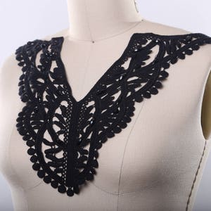 May include: Black lace collar with a scalloped edge. The collar is made of delicate, intricate lace and is perfect for adding a touch of elegance to any outfit.