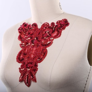 May include: Red beaded lace applique with a floral design. This applique is perfect for adding a touch of elegance to any garment.
