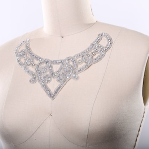 May include: A delicate, silver-toned, beaded embellishment in the shape of a V, perfect for adding a touch of sparkle to a garment.
