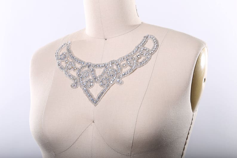 May include: A delicate, silver-toned, beaded embellishment in the shape of a V, perfect for adding a touch of sparkle to a garment.