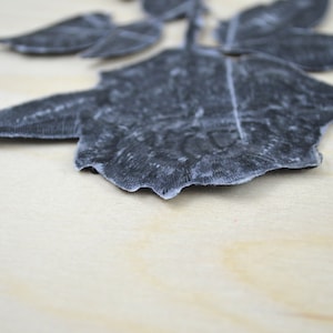 May include: A black velvet rose applique with a textured design. The rose is a single bloom with multiple petals.
