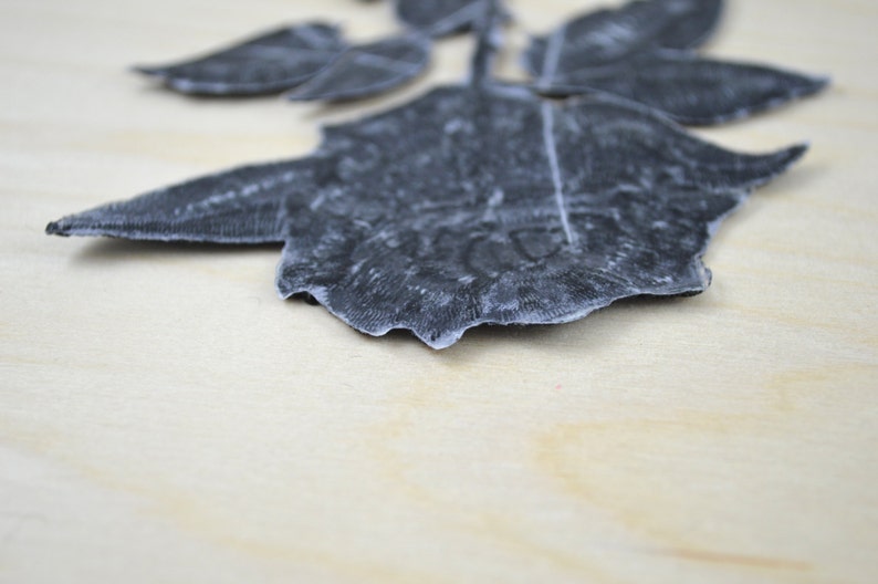 May include: A black velvet rose applique with a textured design. The rose is a single bloom with multiple petals.