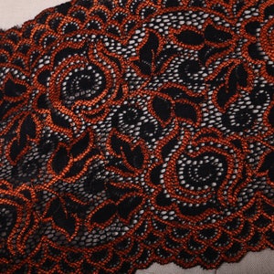 May include: Black lace trim with orange floral embroidery. The lace has a delicate, intricate design.