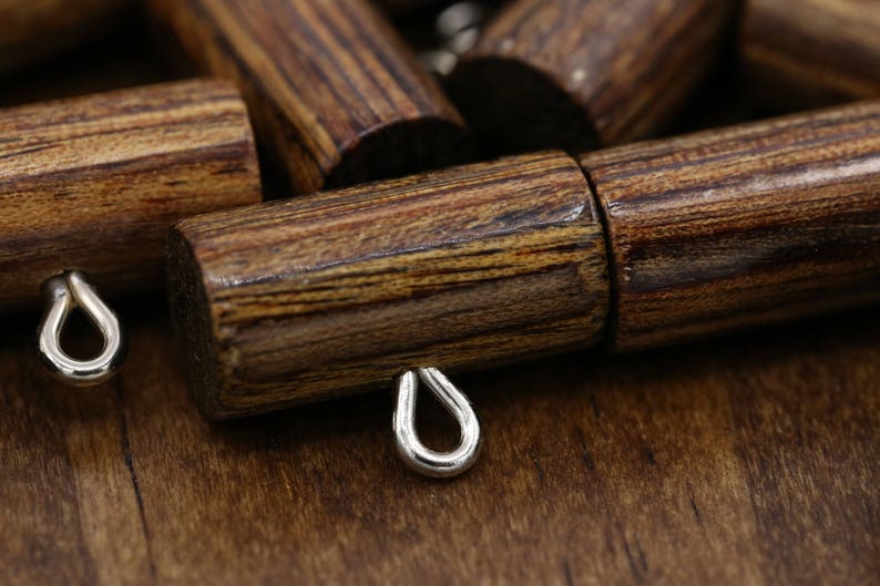 K&ouml;nnte beinhalten: Nahaufnahme einer Reihe von Holzbeh&auml;ltern mit Metallschlaufen. Die Beh&auml;lter sind dunkelbraun mit einer Holzmaserung.