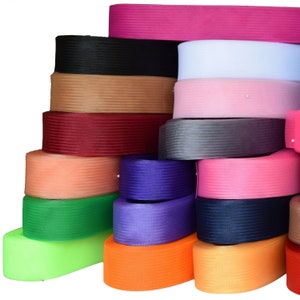 May include: A stack of colorful woven ribbon trim in various colors, including black, brown, red, orange, green, blue, and pink.