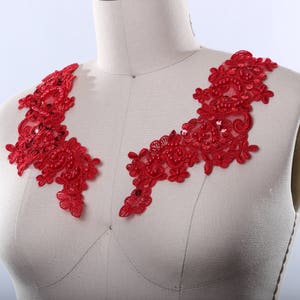 May include: Red beaded lace trim with a floral design. This trim is perfect for adding a touch of elegance to any garment.