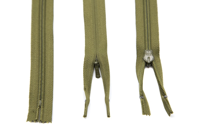 May include: Three green zippers with metal teeth and a slider. The zippers are open and the slider is in the middle of the zipper.