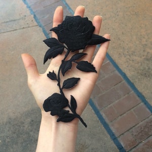 May include: Black fabric rose patch with a stem and leaves. The rose is embroidered with a detailed design.