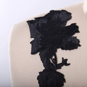 May include: Black velvet floral applique with a large rose design. The applique is perfect for adding a touch of elegance to any garment or project.