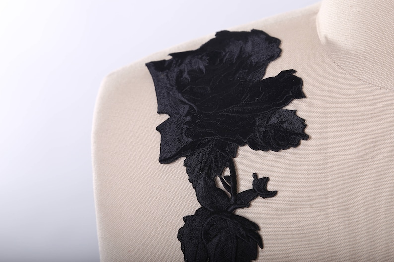 May include: Black velvet floral applique with a large rose design. The applique is perfect for adding a touch of elegance to any garment or project.