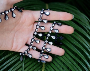 Plastic Rhinestone Tear-Drop Trim Complemented with Acrylic Stones and Real Rhinestones. Available in Black and White