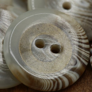 May include: A set of four white and brown striped buttons with two holes. The buttons have a smooth, glossy finish.