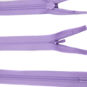May include: Three purple zippers with metal sliders. The zippers are closed, open, and closed.