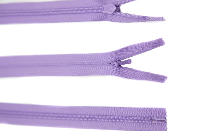May include: Three purple zippers with metal sliders. The zippers are closed, open, and closed.