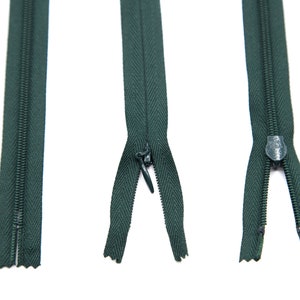 May include: Three green zippers, one closed, one open, and one partially open. The zippers are all the same length and have a dark green color.