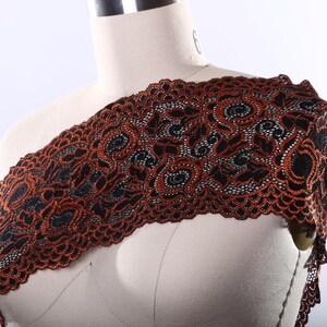 May include: Black and orange lace trim with a floral pattern. The lace is delicate and intricate, with a scalloped edge.
