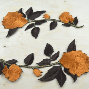 Puede incluir: Dos parches de bordado de rosas de terciopelo marrón con tallos y hojas negras.