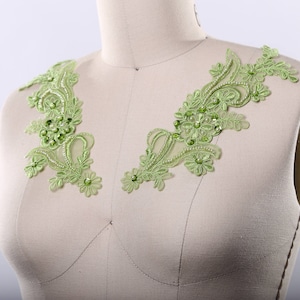 May include: Two green lace appliques with rhinestones, perfect for adding a touch of elegance to a garment.