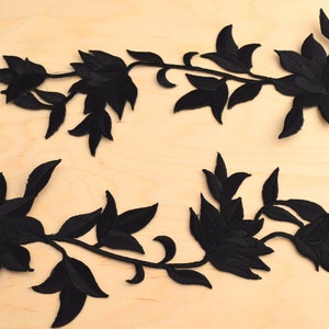 Puede incluir: Dos apliques florales negros con un diseño de vid. Los apliques están hechos de tela y tienen una textura aterciopelada.