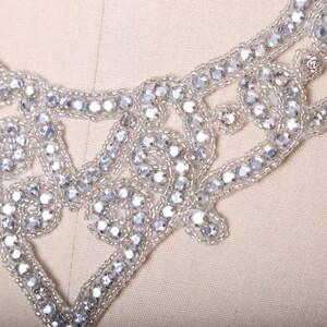 May include: A silver beaded embellishment with a delicate floral design. The embellishment is perfect for adding a touch of sparkle to clothing, accessories, or home decor.