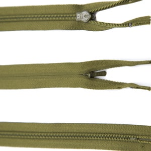 May include: Three olive green zippers with metal sliders. The zippers are open and the slider is in the middle of the zipper.