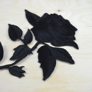 May include: Black velvet rose applique with leaves. This embroidered patch is perfect for adding a touch of elegance to clothing, bags, or home decor projects.