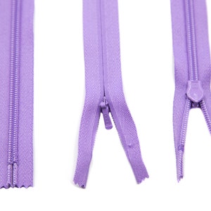 May include: Three purple zippers, each with a different length and a slider. The zippers are on a white background.