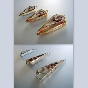 May include: Five shell pendants with gold and silver accents. The pendants are in the shape of a triangle and a long, thin cylinder. The pendants are on a white surface.