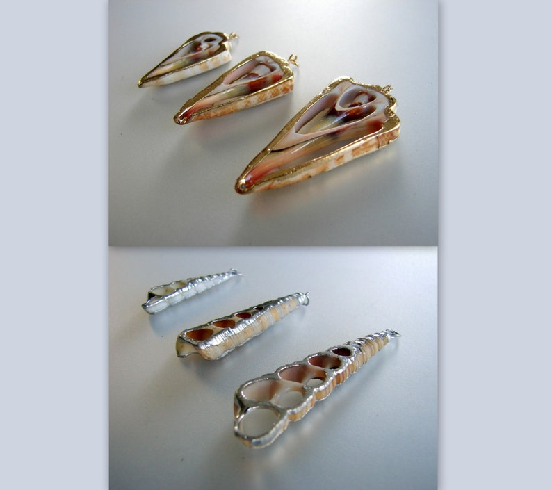 May include: Five shell pendants with gold and silver accents. The pendants are in the shape of a triangle and a long, thin cylinder. The pendants are on a white surface.