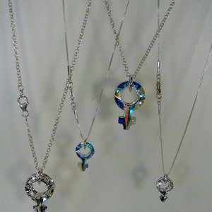 May include: Four silver chains with different length pendants. Each pendant is a silver symbol with a colorful, iridescent glass center.