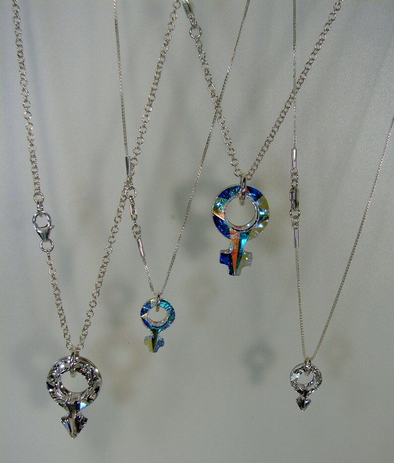 May include: Four silver chains with different length pendants. Each pendant is a silver symbol with a colorful, iridescent glass center.