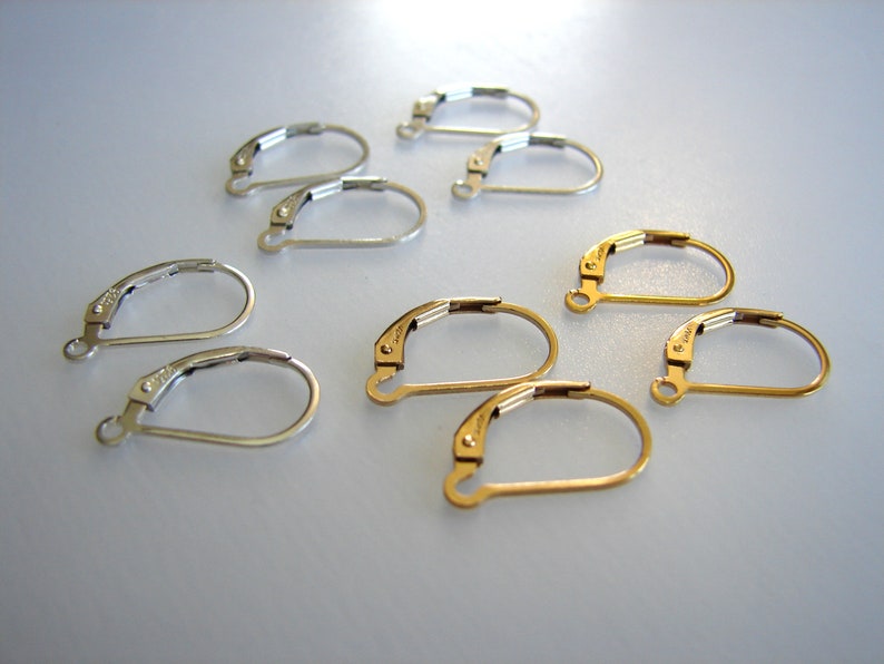 May include: A set of earring findings, including silver and gold-toned options. The findings are made of metal and have a hook closure.