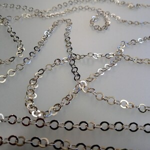 May include: A silver chain necklace with a delicate, round link design. The chain is made of metal and has a shiny finish.