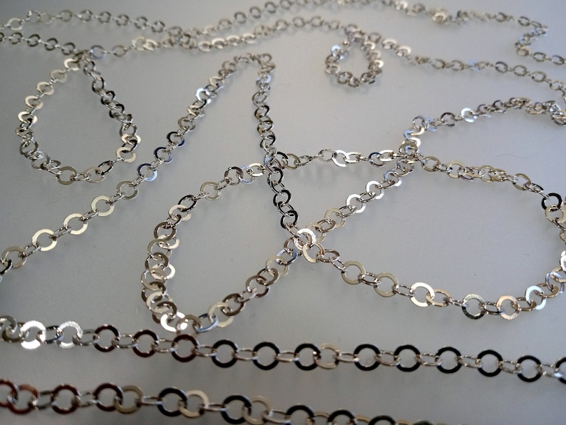 May include: A silver chain necklace with a delicate, round link design. The chain is made of metal and has a shiny finish.