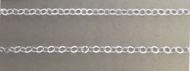 May include: Two rows of silver chain links on a light brown background.