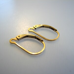 May include: A pair of gold-toned hoop earrings with a hinged closure. The earrings are marked "14K" on the back.