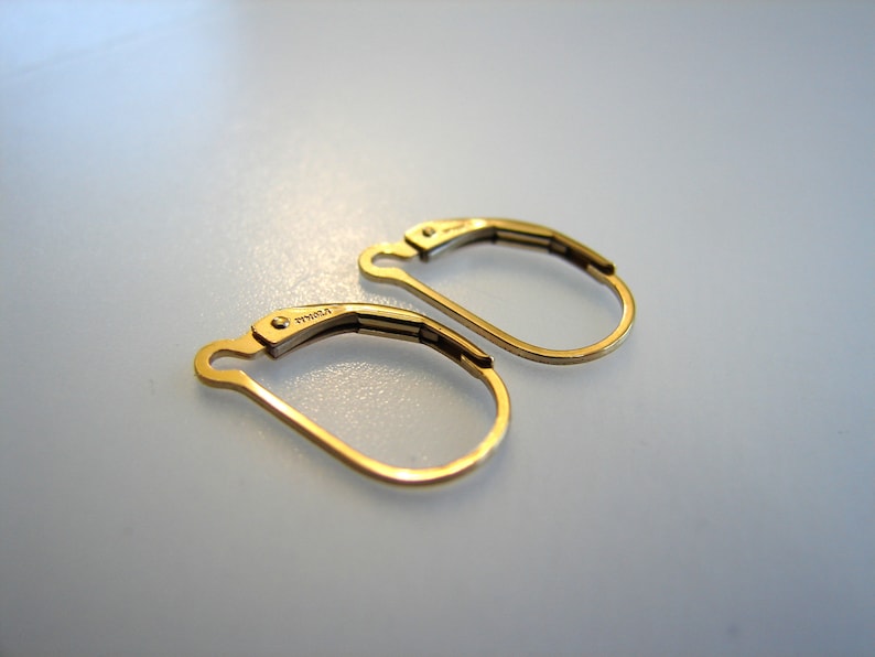 May include: A pair of gold-toned hoop earrings with a hinged closure. The earrings are marked "14K" on the back.