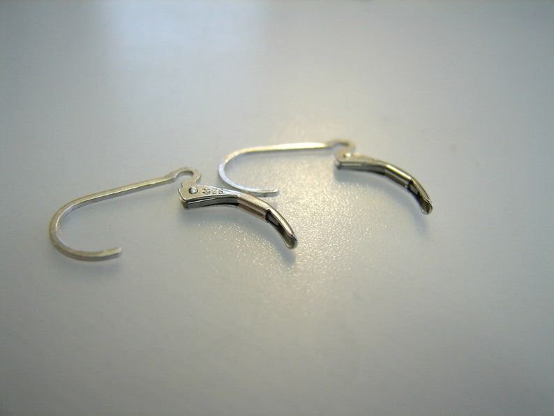 May include: Two silver earring hooks with a spring closure. The hooks are made of metal and have a smooth finish.