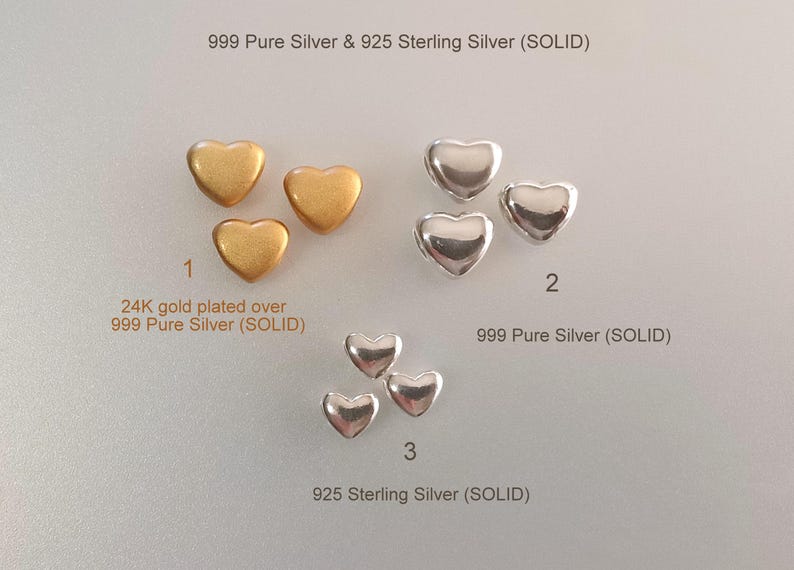 May include: Three groups of small heart-shaped charms labeled 1, 2, and 3. Group 1 features 24K gold plated over 999 pure silver. Group 2 features 999 pure silver. Group 3 features 925 sterling silver. Text reads 999 Pure Silver & 925 Sterling Silver (SOLID).