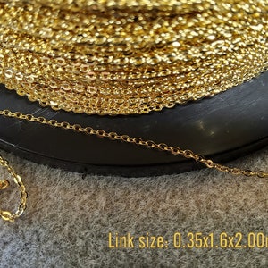 K&ouml;nnte beinhalten: Eine Spule goldfarbener Kette mit einem filigranen, verbundenen Design. Die Kette ist auf einer schwarzen Oberfl&auml;che aufgerollt. Der Text "Link size: 0.35x1.6x2.00mm" ist sichtbar.