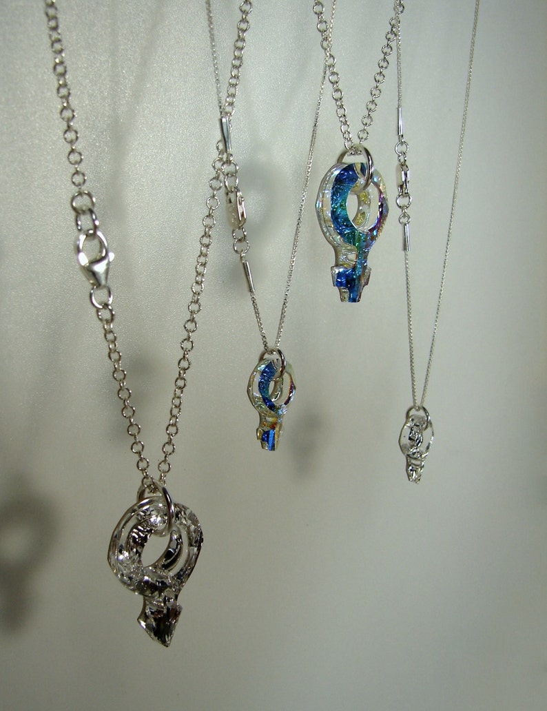May include: Four silver necklaces with different length chains and key-shaped pendants. The pendants are made of iridescent glass with blue, green, and yellow hues.