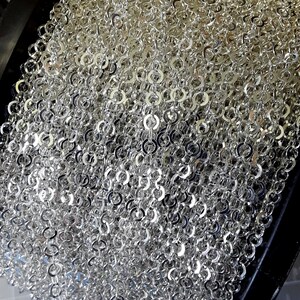 May include: A spool of silver chain link trim. The chain is made of small, round links that are tightly woven together.