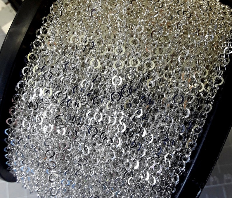 May include: A spool of silver chain link trim. The chain is made of small, round links that are tightly woven together.