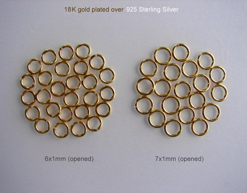 May include: Two groups of gold-plated jump rings, 925 sterling silver. The group on the left is 6 mm in diameter and the group on the right is 7 mm in diameter. Both groups are open.