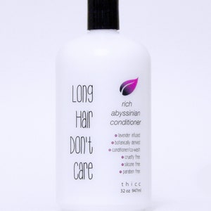 May include: A white plastic bottle of Long Hair Don't Care rich Abyssinian conditioner. The bottle is labeled with a purple leaf logo and the text "Long Hair Don't Care". The bottle is 32 ounces (947 ml) and is labeled as lavender infused, botanically derived, cruelty free, silicone free, and paraben free.