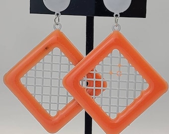 May include: A pair of vintage orange and silver earrings. Each earring features a square orange frame with a silver grid design inside. The earrings are attached to a white circular stud. The earrings are displayed on a black card that reads "Designer Originals" and "Made in Taiwan R.O.C."