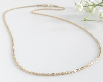 May include: A delicate gold chain necklace. The chain is made of small, round links.